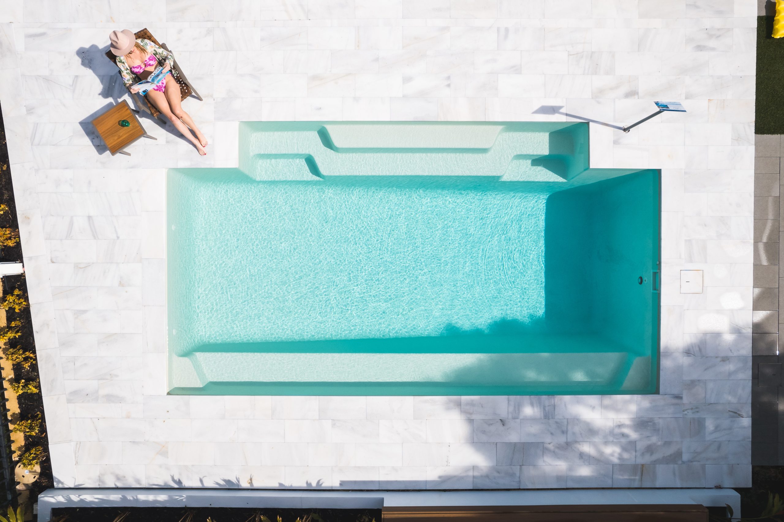 Aerial view of a Bellino fibreglass pool in Sky Blue by Master Pools, surrounded by white stone paving