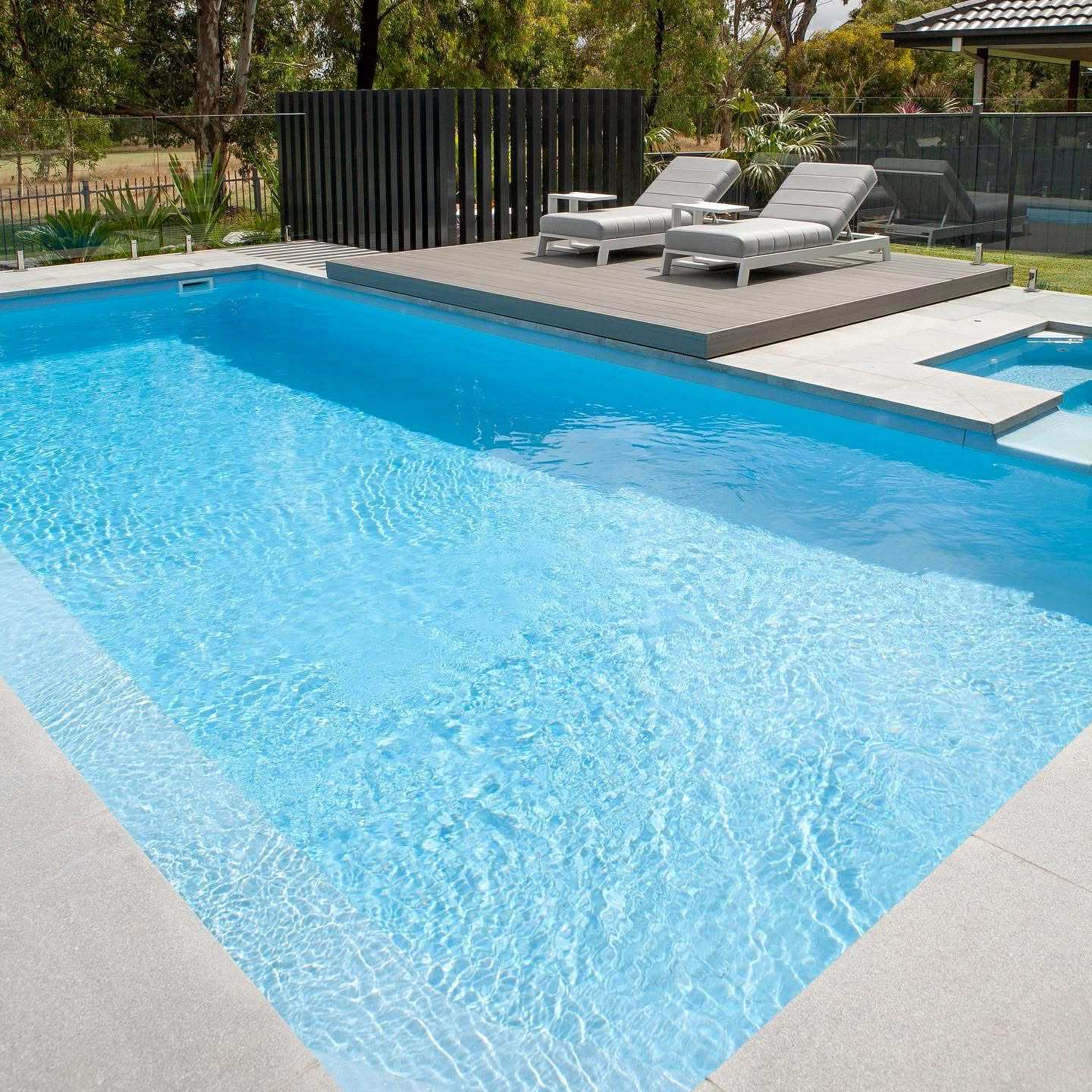 Fibreglass pool with integrated spa, composite deck, and frameless glass fencing by Master Pools in Melbourne
